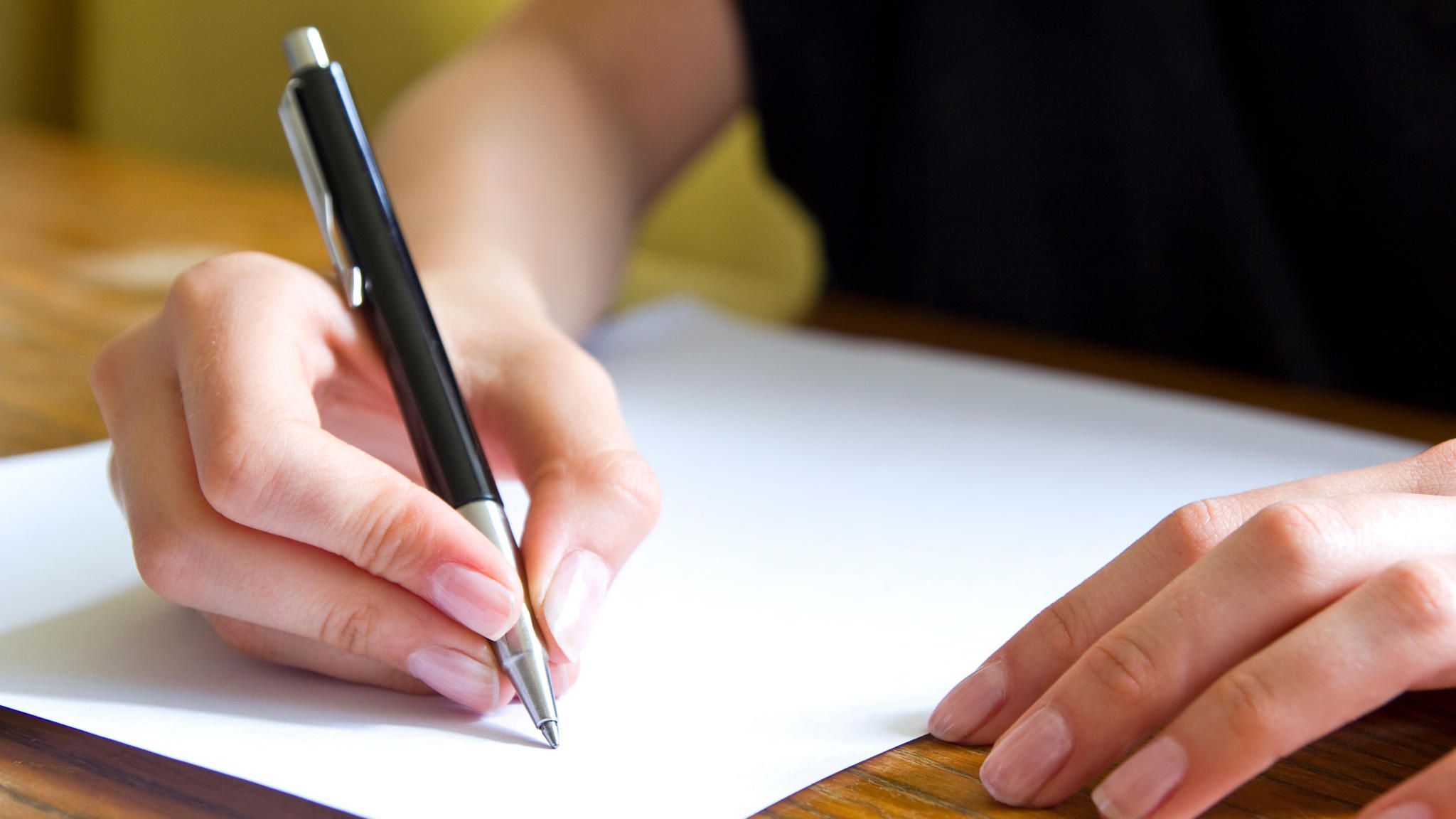 Nahaufnahme einer Hand mit Stift, die einen Brief schreibt