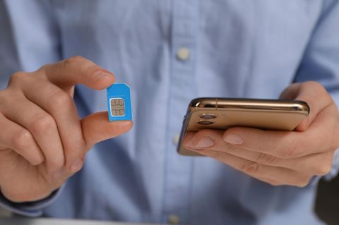 Prepaid-Tarif: Eine Hand hält ein Handy, die andere eine Sim-Karte.