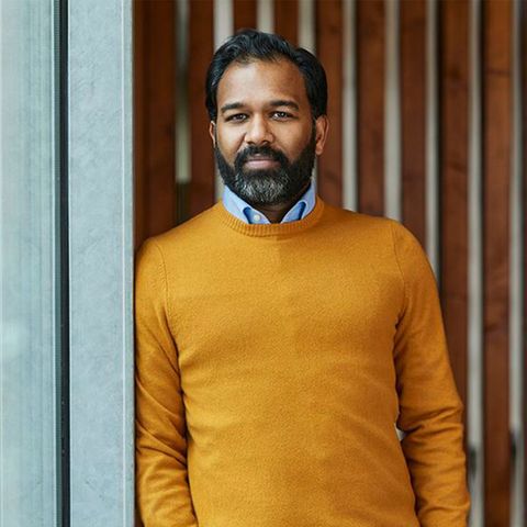 Stephan Anpalagan, Mann of Color im gelben Pullover vor einer Wand, die Kolumne hat das Thema Solingen