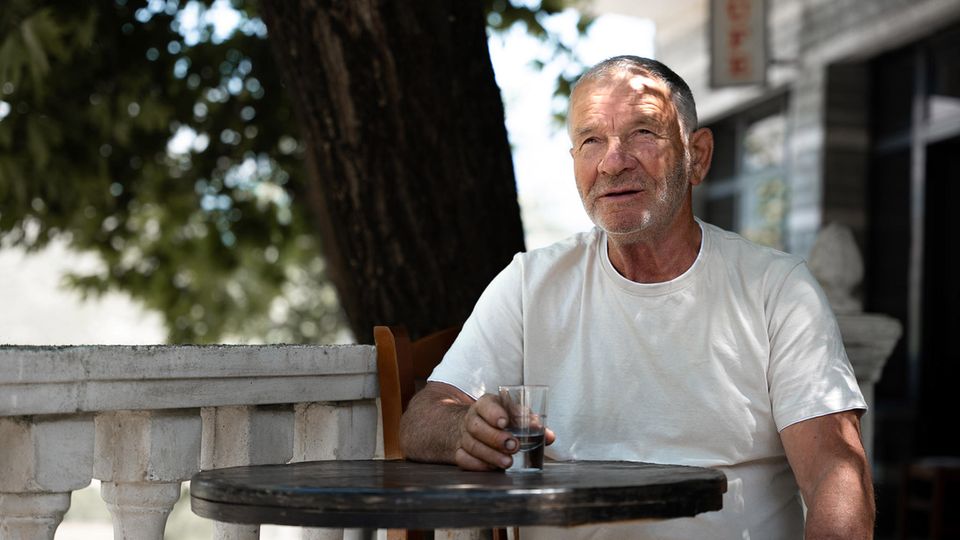 Ein älterer Mann sitzt vor einem Café