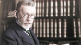 Portrait von Paul Ehrlich in seiner Bibliothek mit einem Buch in der Hand