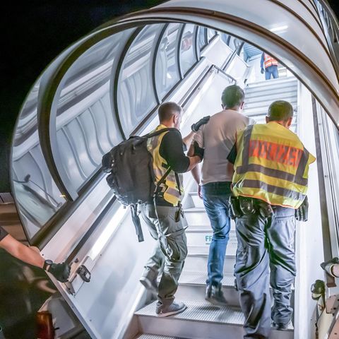 Polizeibeamte begleiten Afghanen am Flughafen bei seiner Abschiebung