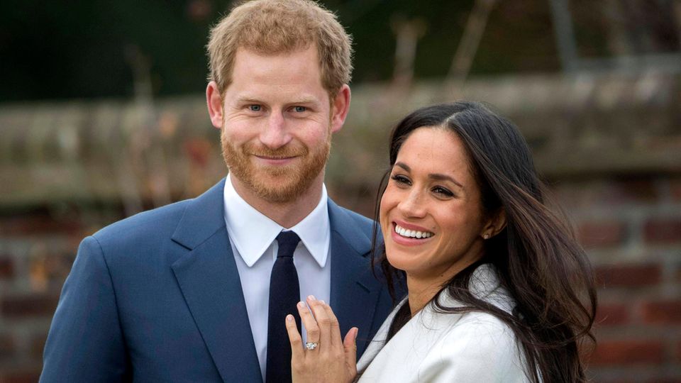 Prinz Harry und seine Frau Meghan lächeln in die Kamera