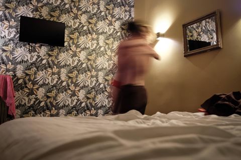 Paar steht halb ausgezogen vor dem Bett und umarmt sich