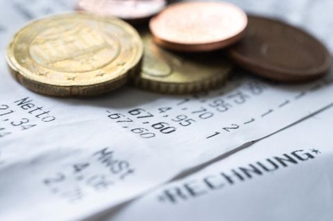 Symboldbild sinkende Inflationsrate: Münzen, die auf einem Kassenbon liegen