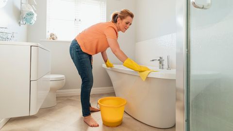 Frau versucht mit einem Tuch die Badewanne zu reinigen