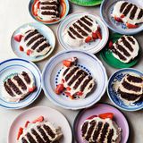 Chocolate Ripple Cake  Was jeder weiß, der schon einmal bei einem australischen Barbecue  war: Chocolate Ripple Cake ist ein allgegenwärtiges No-bake-­ Dessert.  In Australien wird es mit den Schokokeksen Arnott’s Choc Ripple  gemacht, die dann mit Sahne zusammengeklebt werden. Das Rezept  ist so simpel, dass es hinten auf der Packung steht! Kürzlich war  Helen mit ihrer Familie mal wieder in Melbourne, und die Kids waren  so begeistert von dem Dessert, dass sie bettelten, sie möge es für sie  machen, wenn alle wieder in London sind. Da es Helen nicht gelang,  die richtigen Kekse aufzutreiben (inzwischen gibt es sie online), backte  sie selbst welche. Das geht so schnell und einfach, dass Helen nicht  nur welche für den Ripple Cake macht, sondern immer einige extra.  Keine Geburtstagsparty (und keine Grillparty) ist ohne sie komplett.     Vorbereiten: Die Kekse können bis zu 7 Tage im Voraus vorbereitet und  gebacken werden. In einem luftdicht verschließbaren Behälter aufbewahren.  Der Ripple Cake muss bis zu 6 Stunden vor dem Servieren  fertiggestellt werden, damit er durchziehen kann, lässt sich aber auch  bis zu 2 Tage im Voraus herstellen (im Kühlschrank aufbewahren).  Ausprobieren: Die Erdbeeren machen sich hier gut, aber als Alternative  könnt ihr 1 Keks oder Borkenschokolade darüberkrümeln.     Zutaten:  3 EL Milch (oder 105 ml, wenn kein Grand Marnier verwendet wird)  60 ml Grand Marnier (nach Belieben)  1 Espresso, normal oder entkoffeiniert (30 ml)  650 g Sahne (oder Crème double)  325 g Crème fraîche  50 g Puderzucker  1½ TL Vanilleextrakt  1½ TL gemahlener Zimt  Kekse  225 g Mehl  50 g Kakaopulver  ¾ TL Backpulver  ½ TL Speisenatron  ¼ TL Salz  100 g weiche Butter  200 g Zucker  50 ml Öl  50 g heller Zuckerrübensirup (z. B. Golden Syrup), plus Sirup zum Anrichten (nach Belieben)  1 Ei  Marinierte Erdbeeren  600 g Erdbeeren, von den Kelchblättern befreit, dann geviertelt  1½ EL Zucker  1 TL fein abgeriebene Schale von 1 Bio-Orange  2 EL Grand Marnier (oder Orangensaft)  2 Zesten von 1 Bio-Orange, in feinste lange Fäden geschnitten     Zubereitung:  Für 8–10 Personen  Für die Kekse Mehl, Kakaopulver, Backpulver, Speisenatron und Salz in  eine Schüssel sieben.  Butter, Zucker, Öl und Sirup in die Schüssel einer mit dem Flachrüh-  rer bestückten Küchenmaschine füllen. Auf mittlerer Stufe 2 Minuten  schlagen, bis die Mischung hell und cremig ist. Die Schüsselwände  nach unten abschaben, das Ei dazu aufschlagen alles vermengen, bis  es untergearbeitet ist. Niedrige Stufe einstellen, die trockenen Zutaten  hinzufügen und rühren, bis der Teig bindet. Diesen einwickeln und für  mindestens 2 Stunden in den Kühlschrank legen.  Wenn gebacken werden kann, den Backofen auf 170 °C (Umluft)  vorheizen.  Vom Teig kleine Stücke (à ca. 30 g) abzupfen und zu Kugeln rollen.  Diese mit etwa 5 cm Abstand zueinander auf zwei mit Backpapier  ausgelegte Backbleche setzen. Es sollten etwa 23 Kugeln sein. Mit der  Hand flach drücken – sie sollen etwa Ø 5 cm haben  –, dann 15 Minuten im Ofen backen, bis sie fest und oben aufgerissen sind. Aus dem Ofen  nehmen und 5 Minuten abkühlen lassen, bevor sie zum vollständigen  Auskühlen auf ein Gitter gelegt werden.