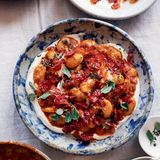 Weiße Riesenbohnen mit gerösteten Kirschtomaten  Besorgt euch hierfür, wenn möglich, weiße Riesenbohnen (Judiones oder Gigantes) aus dem Glas. Sie sind weicher, buttriger und viel cremiger als die kleineren (die in Dosen daherkommen). Dieses Gericht eignet sich gut als Teil einer Mezze-Tafel, kann aber auch gegessen werden, wie es ist, mit zerkrümeltem Feta oder Oliven als Topping.  Aufbewahren: Das fertige Gericht hält sich im Kühlschrank bis zu 3 Tage. Vor dem Servieren wieder Zimmertemperatur annehmen lassen. Es lohnt sich, die knusprigen Tomatenhäute immer im Haus zu haben, für Salate oder Pastagerichte. Das Rezept dafür stammt aus einem Restaurant namens Bar Rochford in Canberra, Australien, wo sie mit frischen grünen Bohnen serviert werden. In einem fest verschlossenen Einmachglas halten sie sich bis zu 1 Woche.     Zutaten:  500 g Kirschtomaten  85 ml Olivenöl  1 Zwiebel, fein gewürfelt (150 g)  2 Knoblauchzehen, in dünne Scheiben geschnitten  2 TL getrockneter Oregano  2 TL Thymianblättchen, grob gehackt, plus einige ganze Thymianblättchen zum Garnieren  1 TL Fenchelsamen, geröstet und leicht zerstoßen  1 Lorbeerblatt  80 ml trockener Weißwein  2 TL geräuchertes Paprikapulver  1 Glas weiße Riesenbohnen (700 g), abgetropft und abgespült  Salz und frisch gemahlener  schwarzer Pfeffer  Zum Servieren  75 g griechischer Joghurt  dicke Scheiben helles Sauer­teigbrot (oder anderes knuspriges Brot), getoastet (nach Belieben)     Zubereitung:  Für 4 Personen  Den Backofen auf 210 °C (Umluft) vorheizen.  Die Tomaten mit 2 TL Öl durchheben und auf einem mit Backpapier  ausgelegten Backblech verteilen. Im Ofen 20 Minuten rösten, bis die  Häute sich abgelöst haben und die Tomaten weich und ein wenig  geschrumpft sind. Aus dem Ofen nehmen und die Tomaten mitsamt  dem ausgetretenen Saft zum Abkühlen in eine flache Schüssel füllen.  Auf das Blech frisches Backpapier legen und die Ofentemperatur auf  100 °C (Umluft) reduzieren.  Sobald die Tomaten so weit abgekühlt sind, dass man sie anfassen  kann, die Häute abziehen und diese auf das ausgelegte Blech legen.  Das Blech wieder in den Ofen schieben und die Häute etwa 45 Minuten  rösten, bis sie trocken und knusprig sind, dabei immer wieder kräftig  durchrühren. Die gehäuteten Tomaten beiseitestellen.  Die restlichen 75 ml Öl in einem Topf bei mittlerer Temperatur erhitzen.  Zwiebel und Knoblauch darin mit Oregano, Thymian, Fenchelsamen  und Lorbeer 10–12 Minuten anschwitzen, bis die Zwiebelwürfel weich  sind, aber kaum Farbe angenommen haben. Den Wein angießen und  2 Minuten einkochen lassen, dann das Paprikapulver unterrühren. Alles  1 Minute anschwitzen. Das Fruchtfleisch der Tomaten mit 1 TL Salz hin-  zufügen. Das Ganze 15 Minuten schwach köcheln lassen, dabei häufig  rühren, damit die Tomaten zerfallen. Die Bohnen mit reichlich Pfeffer  unterrühren. Etwa 2 Minuten heiß werden lassen, dann vom Herd  nehmen. Den Joghurt auf einer Servierplatte verstreichen und die   Bohnenmischung daraufhäufen. Die getrockneten Tomatenhäute darüberkrümeln.  Alles mit Thymianblättern bestreuen und nach Belieben mit  Brot zum Auftunken servieren.