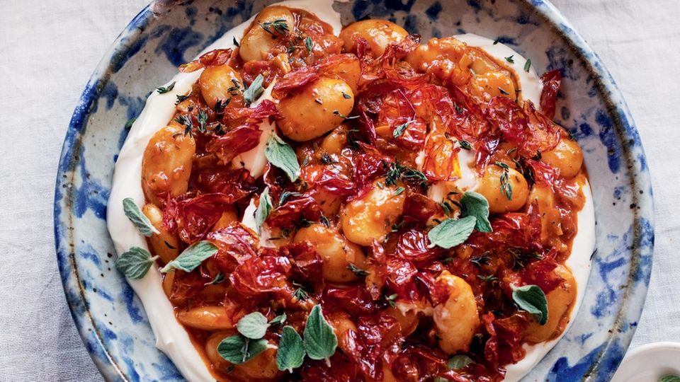 Weiße Riesenbohnen mit gerösteten Kirschtomaten  Besorgt euch hierfür, wenn möglich, weiße Riesenbohnen (Judiones oder Gigantes) aus dem Glas. Sie sind weicher, buttriger und viel cremiger als die kleineren (die in Dosen daherkommen). Dieses Gericht eignet sich gut als Teil einer Mezze-Tafel, kann aber auch gegessen werden, wie es ist, mit zerkrümeltem Feta oder Oliven als Topping.  Aufbewahren: Das fertige Gericht hält sich im Kühlschrank bis zu 3 Tage. Vor dem Servieren wieder Zimmertemperatur annehmen lassen. Es lohnt sich, die knusprigen Tomatenhäute immer im Haus zu haben, für Salate oder Pastagerichte. Das Rezept dafür stammt aus einem Restaurant namens Bar Rochford in Canberra, Australien, wo sie mit frischen grünen Bohnen serviert werden. In einem fest verschlossenen Einmachglas halten sie sich bis zu 1 Woche.     Zutaten:  500 g Kirschtomaten  85 ml Olivenöl  1 Zwiebel, fein gewürfelt (150 g)  2 Knoblauchzehen, in dünne Scheiben geschnitten  2 TL getrockneter Oregano  2 TL Thymianblättchen, grob gehackt, plus einige ganze Thymianblättchen zum Garnieren  1 TL Fenchelsamen, geröstet und leicht zerstoßen  1 Lorbeerblatt  80 ml trockener Weißwein  2 TL geräuchertes Paprikapulver  1 Glas weiße Riesenbohnen (700 g), abgetropft und abgespült  Salz und frisch gemahlener  schwarzer Pfeffer  Zum Servieren  75 g griechischer Joghurt  dicke Scheiben helles Sauer­teigbrot (oder anderes knuspriges Brot), getoastet (nach Belieben)     Zubereitung:  Für 4 Personen  Den Backofen auf 210 °C (Umluft) vorheizen.  Die Tomaten mit 2 TL Öl durchheben und auf einem mit Backpapier  ausgelegten Backblech verteilen. Im Ofen 20 Minuten rösten, bis die  Häute sich abgelöst haben und die Tomaten weich und ein wenig  geschrumpft sind. Aus dem Ofen nehmen und die Tomaten mitsamt  dem ausgetretenen Saft zum Abkühlen in eine flache Schüssel füllen.  Auf das Blech frisches Backpapier legen und die Ofentemperatur auf  100 °C (Umluft) reduzieren.  Sobald die Tomaten so weit abgekühlt sind, dass man sie anfassen  kann, die Häute abziehen und diese auf das ausgelegte Blech legen.  Das Blech wieder in den Ofen schieben und die Häute etwa 45 Minuten  rösten, bis sie trocken und knusprig sind, dabei immer wieder kräftig  durchrühren. Die gehäuteten Tomaten beiseitestellen.  Die restlichen 75 ml Öl in einem Topf bei mittlerer Temperatur erhitzen.  Zwiebel und Knoblauch darin mit Oregano, Thymian, Fenchelsamen  und Lorbeer 10–12 Minuten anschwitzen, bis die Zwiebelwürfel weich  sind, aber kaum Farbe angenommen haben. Den Wein angießen und  2 Minuten einkochen lassen, dann das Paprikapulver unterrühren. Alles  1 Minute anschwitzen. Das Fruchtfleisch der Tomaten mit 1 TL Salz hin-  zufügen. Das Ganze 15 Minuten schwach köcheln lassen, dabei häufig  rühren, damit die Tomaten zerfallen. Die Bohnen mit reichlich Pfeffer  unterrühren. Etwa 2 Minuten heiß werden lassen, dann vom Herd  nehmen. Den Joghurt auf einer Servierplatte verstreichen und die   Bohnenmischung daraufhäufen. Die getrockneten Tomatenhäute darüberkrümeln.  Alles mit Thymianblättern bestreuen und nach Belieben mit  Brot zum Auftunken servieren.