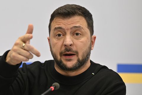 Ukraines Präsident Wolodymr Selenskyj sitzt auf einem Podium