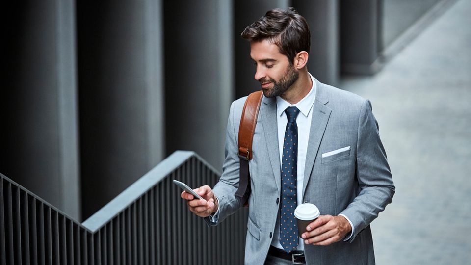 Business-Handytarif: Mann in Anzug läuft mit Handy in der Hand eine Treppe hoch.