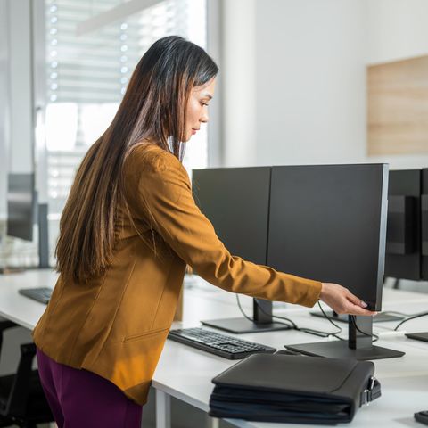 Monitor höhenverstellbar: Eine Frau stellt die Höhe der Bildschirme ein