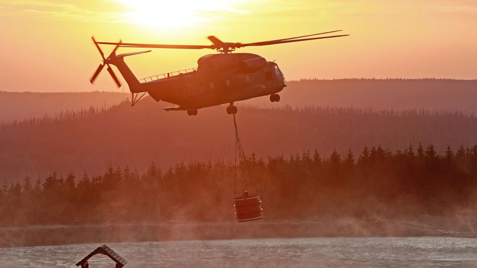 Ein Hubschrauber der Bundeswehr fliegt mit einem Wasserbehälter zum Königsberg am Brocken