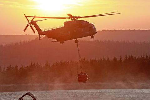 Ein Hubschrauber der Bundeswehr fliegt mit einem Wasserbehälter zum Königsberg am Brocken
