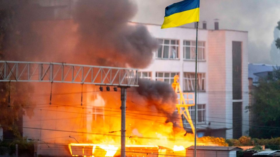 The flag of Ukraine in front of thick smoke after a Russian missile attack on Kyiv