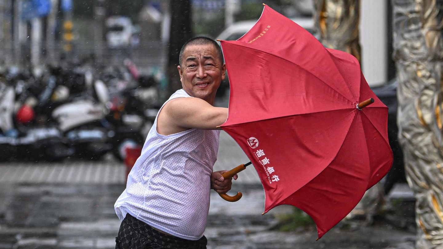 Ein Mann in der chinesischen Stadt Haikou kämpft mit seinem Regenschirm