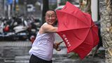 Ein Mann in der chinesischen Stadt Haikou kämpft mit seinem Regenschirm