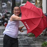 Ein Mann in der chinesischen Stadt Haikou kämpft mit seinem Regenschirm