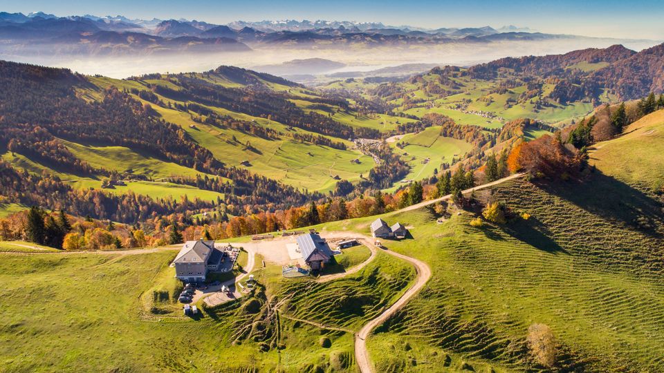 Luftbild: Blick auf die herbstliche Chrüzegg mit Hütten und Bergpanorama