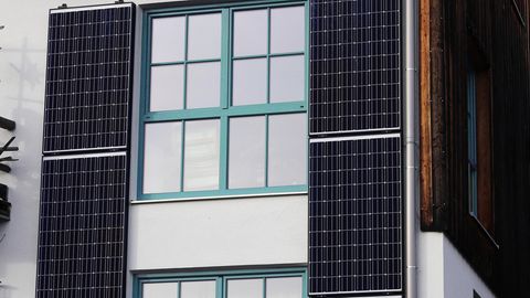 Solarmodule an einer Häuserfassade neben den Fenstern