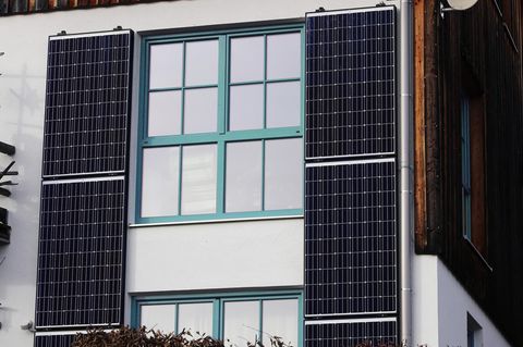 Solarmodule an einer Häuserfassade neben den Fenstern