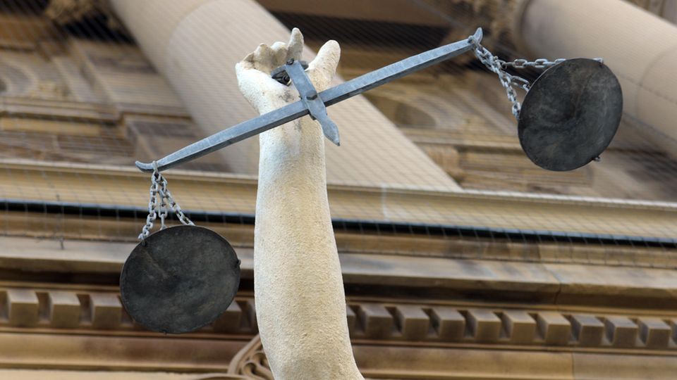 Vor einem Justizgebäude steht eine Statue der Göttin Justitia