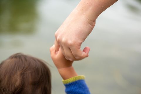 Familie: die Hand eines Erwachsenen hält die Hand eines Kindes