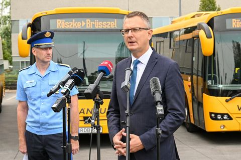 Ungarns Vize-Innenminister Bence Retvari steht vor Bussen "Röszke - Brüssel" steht