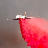 Ein Flugzeug wirft über dem Trabucco Canyon in Kalifornien Löschmittel über einem der Waldbrände ab