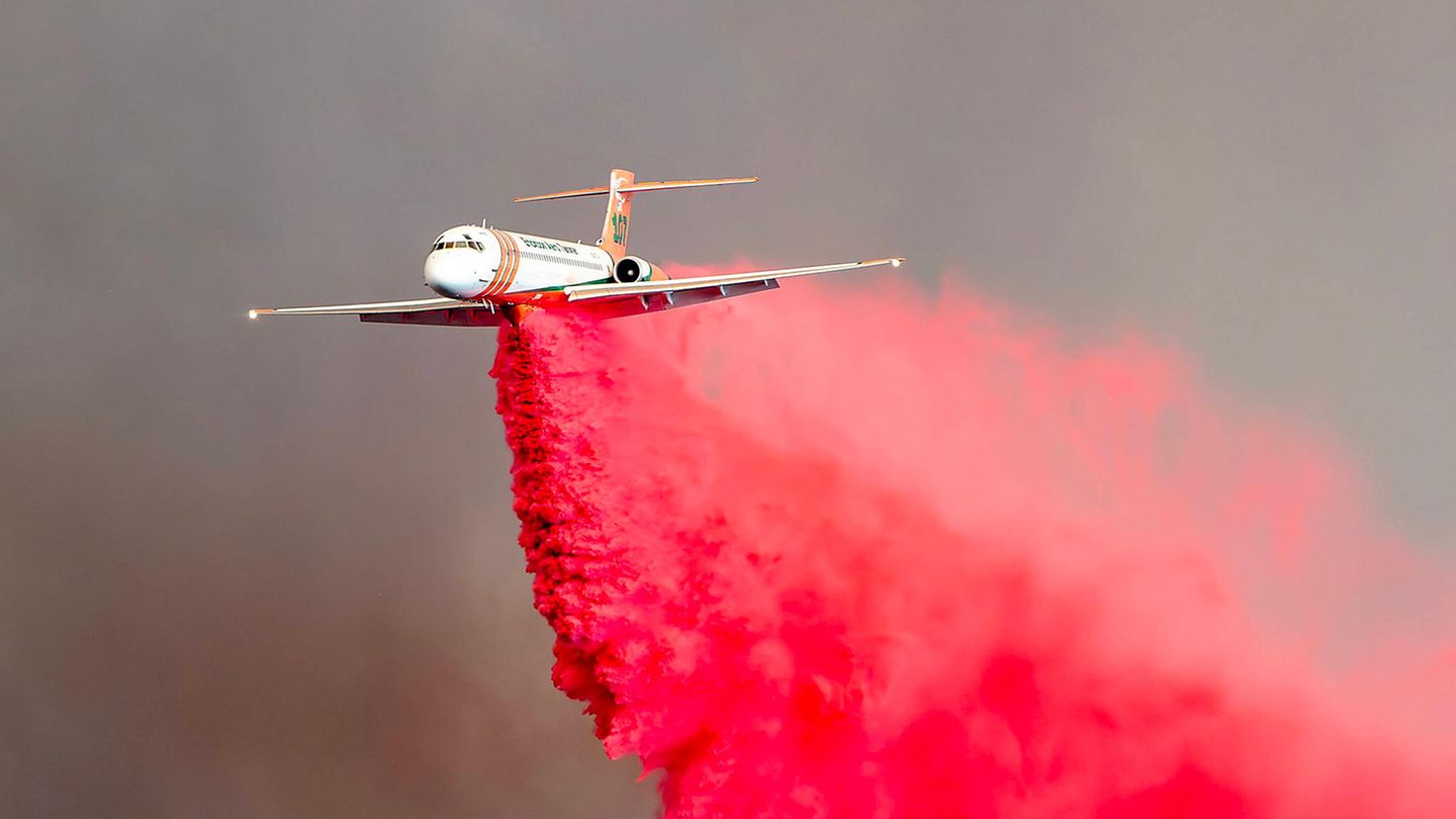 Ein Flugzeug wirft über dem Trabucco Canyon in Kalifornien Löschmittel über einem der Waldbrände ab