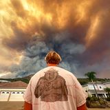 Aidan Thomas trägt ein "Smokey Bear"-T-Shirt, während er beobachtet, wie der Rauch des Airport Fire hinter der Meander Lane aufsteigt