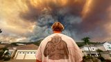 Aidan Thomas trägt ein "Smokey Bear"-T-Shirt, während er beobachtet, wie der Rauch des Airport Fire hinter der Meander Lane aufsteigt