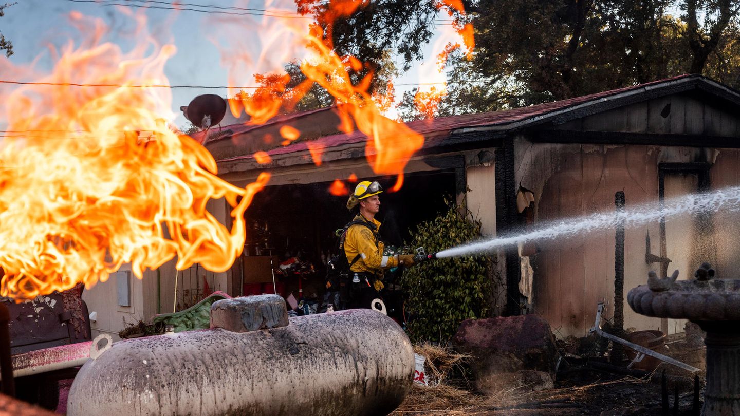 Feuerwehrmann Nolan Graham sprüht Wasser um eine verbrannte Garage, während das Boyles-Feuer in Clearlake, Kalifornien, brennt