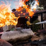 Feuerwehrmann Nolan Graham sprüht Wasser um eine verbrannte Garage, während das Boyles-Feuer in Clearlake, Kalifornien, brennt