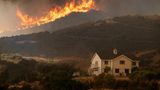 Am Lake Elsinore nähert sich das Airport Fire einem Haus. In mehreren Bezirken im Süden des Bundesstaates wurden Anwohner mittlerweile aufgefordert, sich aus der Gefahrenzone in Sicherheit zu bringen. Noch steht hier aber ein Auto vor dem Haus. Sind die Bewohner noch da – oder mit einem anderen Fahrzeug geflohen? 