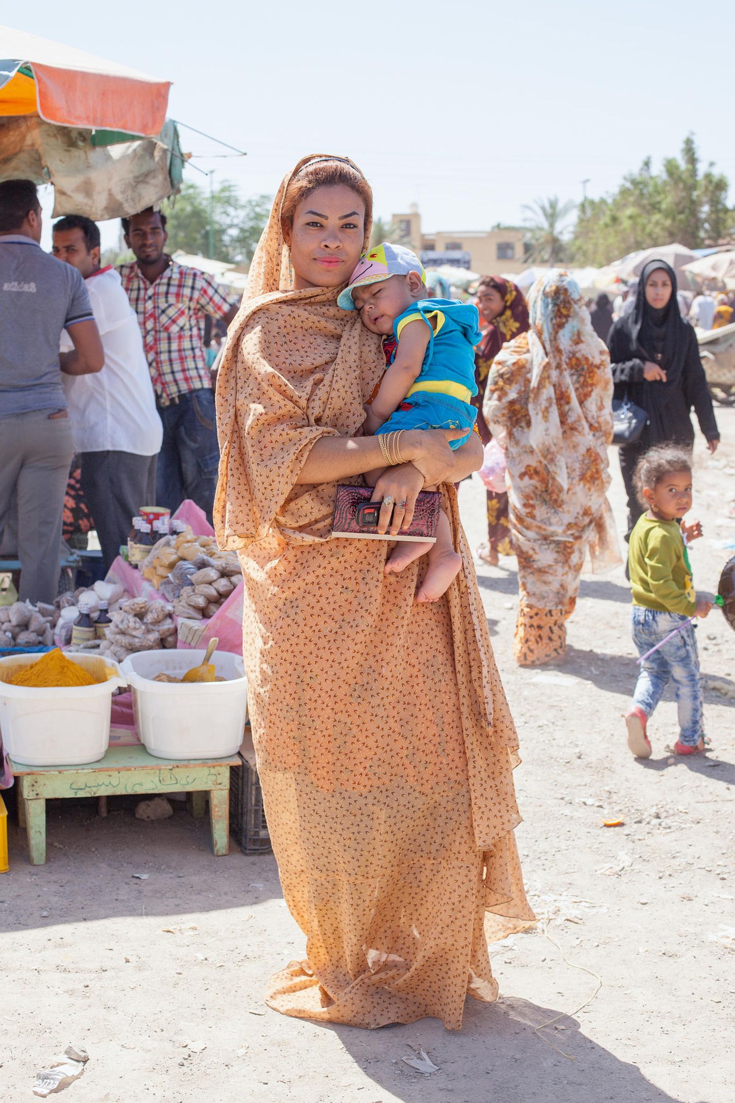 Eine junge, selbstbewusste Frau (Afro-Iranerin) hält ein schlafendes Baby im Arm. Eine junge, selbstbewusste Frau (Afro-Iranerin) hält ein schlafendes Baby im Arm.