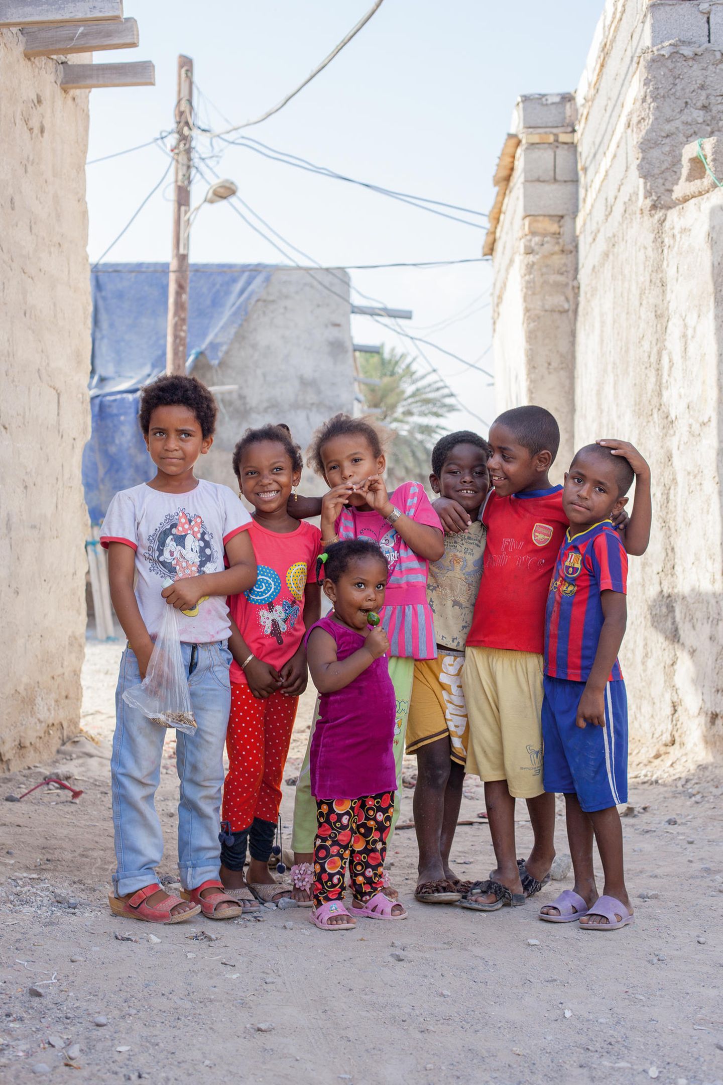 Sieben Kinder unterschiedlichen Alters (Afro-Iraner) stehen nebeneinander.