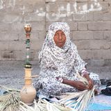Eine afro-iranische Frau mit Kopftuch sitzt im Schneidersitz auf dem Boden.