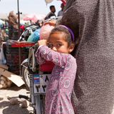 Ein afro-iranisches Kind hält sich am Gepäckträger eines Motorads fest.