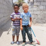 Zwei kleine Jungen (Afro-Iraner) im Kindergartenalter stehen vor unverputzen Wänden.
