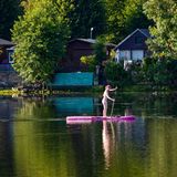 Stand-up-Paddlerin vor Ufer mit Schrebergärten
