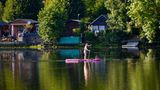 Stand-up-Paddlerin vor Ufer mit Schrebergärten
