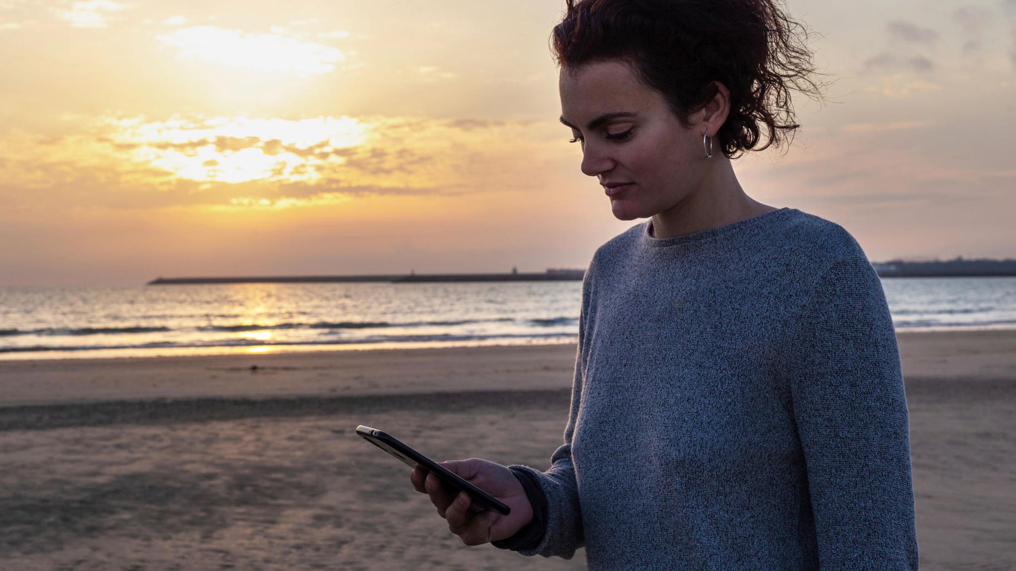 Frau schaut beim Online-Dating auf ihr Handy am Strand