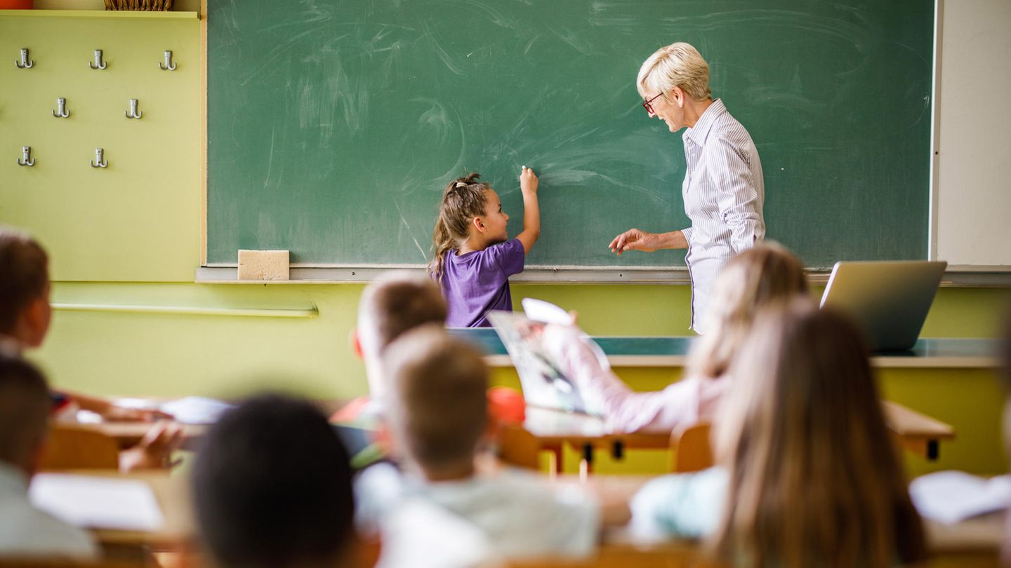 Lehrerin steht mit junger Schülerin an der Tafel
