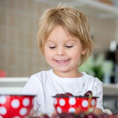 Ein kleiner Junge vor Schüsseln mit Obst und Gemüse
