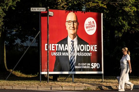 Eine Frau spaziert an einer großen Wahlplakatwand der SPD zur Brandenburg-Wahl mit Dietmar Woidke vorbei