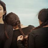 drei Mädchen im Anschnitt teils von Hinten mit langen braunen Zöpfen und schwarzer Kleidung