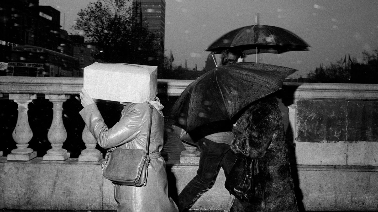 Menschen laufen bei Regen über die O'Connell Bridge