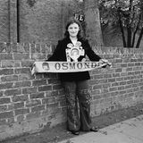 Ein kleines Mädchen dass ein Fan der Osmonds ist hält einen Fan Schal hoch