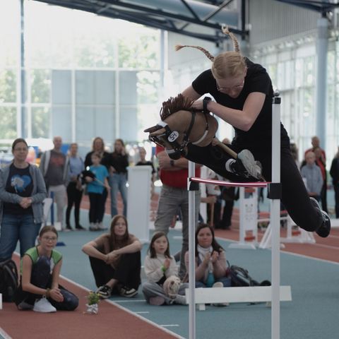 Hobby Horsing: Mädchen springt mit Steckenpferd über ein Hindernis